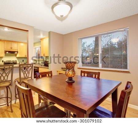 Dining square room table with light wood kitchen behind.