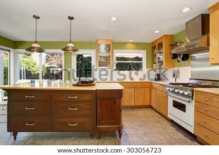Unique kitchen with green walls, tile floor, and lovely white counter tops.