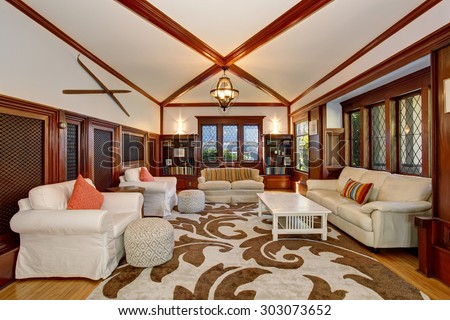 Authentic living room with brown and white decorative rug, also including hardwood flor and white sofas.