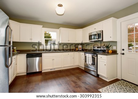 Classic kitchen with green interior paint, hardwood floor, and white cabinets.