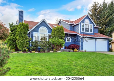 Large blue house with white trim, and well kept lawn, along with two garage spaces.