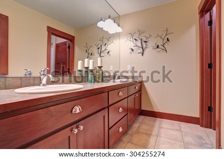 Nice bathroom with tile floor and red wood cabinets.