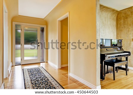 House interior. Entrance hallway with glass door, hardwood floor and  rug. View of piano