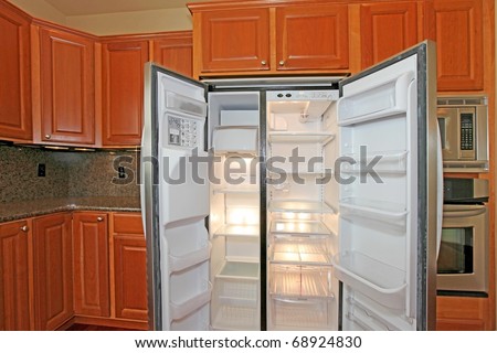 Open empty refrigerator with cherry cabinets