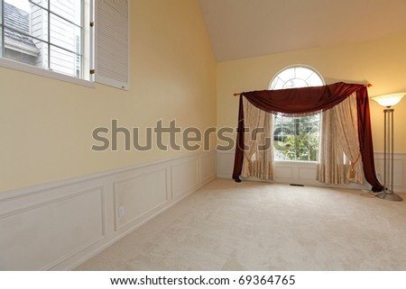 Empty living room with large window with red curtains and white molding