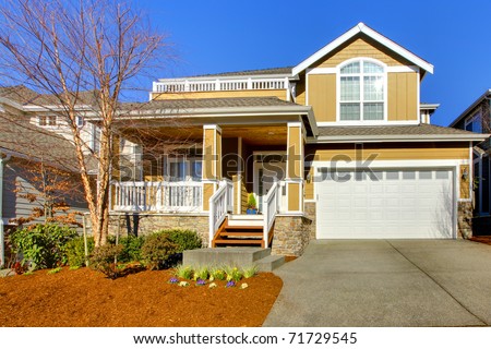 Yellow mustard house with white trim and spring landscape.