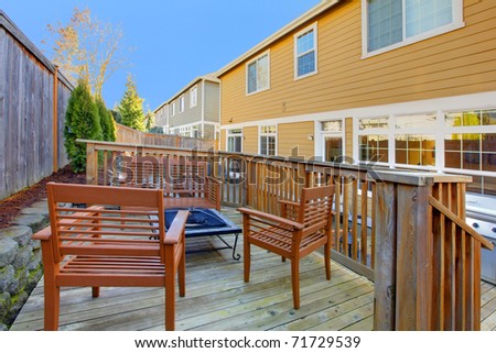Back yard of mustard house with porch and outdoor furniture.