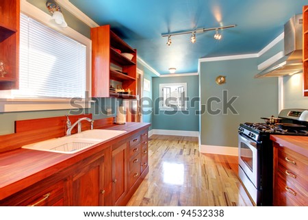 Blue kitchen with cherry cabinets and shiny light floor.