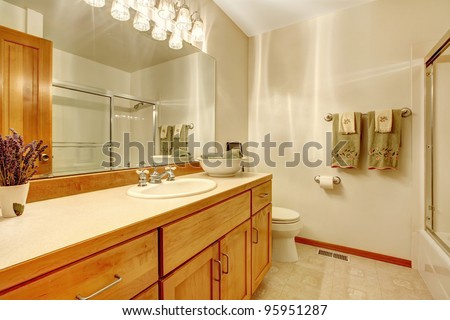 Simple white bathroom with wood cabinets,