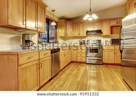 Kitchen with golden wood  cabinets and hardwood floor. Simple American home.