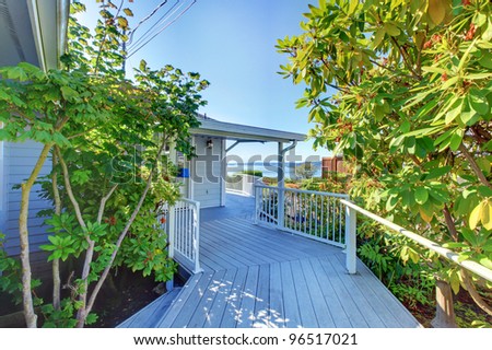 Grey house front door exterior with wood deck walkway and water view.