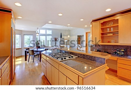 Large luxury modern wood kitchen with granite counter tops and yellow hardwood floor.