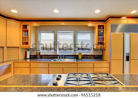Large luxury modern wood kitchen with granite counter tops and yellow hardwood floor.