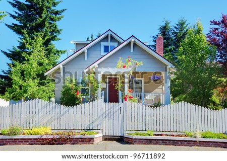 Cute small grey old craftsman style house with white fence.
