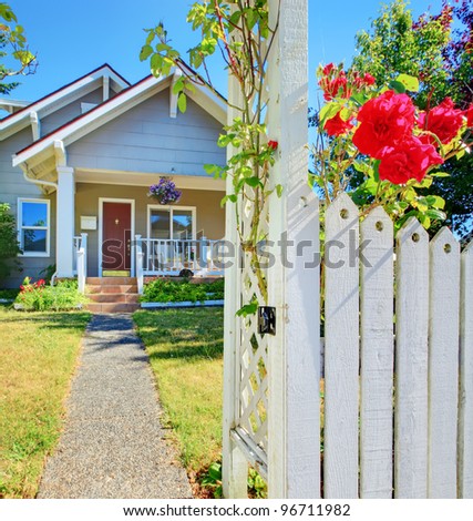 Small American house and white fence with red roses.