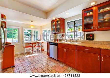 Cherry wood kitchen with tile floor and sunny table home interior.