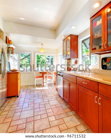 Cherry wood kitchen with tile floor and sunny table home interior.