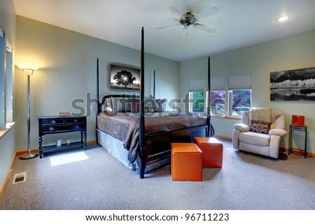 Large bedroom with five windows and black post bed with brown bedding. Modern and classic comfortable design.