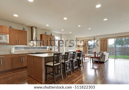 Bright modern open plan kitchen room interior. Large bar style island with stools and polished hardwood floors. Northwest, USA