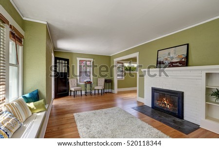Living room interior design of craftsman home with white brick fireplace, built-in shelves, window seat with pillows, pale green walls and hardwood floor. Northwest, USA