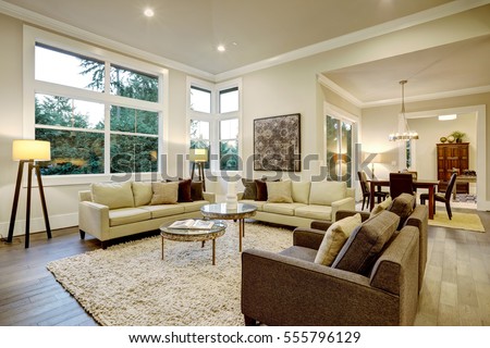 Chic light living room design with dark floors. Furnished with glass top accent tables and beige sofas topped with brown pillows . Northwest, USA