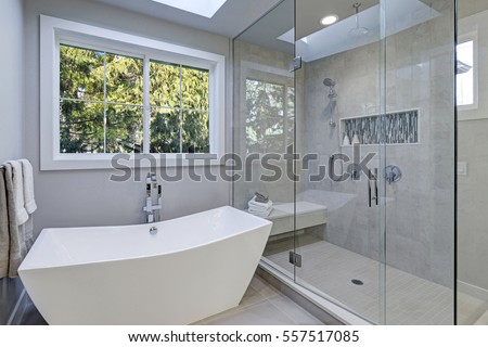 Glass walk-in shower with gray subway tiled surround and white freestanding tub in new luxury home bathroom. Northwest, USA