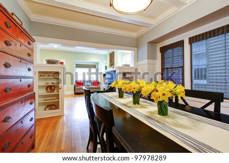 Dining room interior with large black table and wood dresser with grey blue walls.
