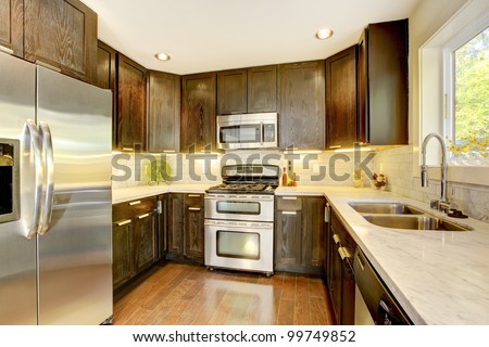 Modern luxury new dark brown and white kitchen with stainless steal appliances.