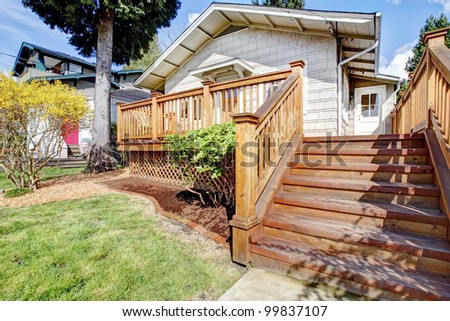 Small white house with wood deck and steps.