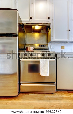 Stove and refrigerator in stainless steal with white kitchen and hardwood floor.