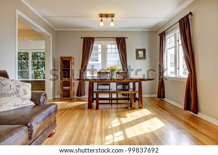 Dining room with brown curtain and hardwood floor and leather sofa.