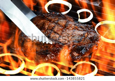 Delicious juicy rib eye steak on a barbecue grill with flames