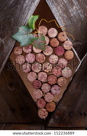Wine corks in shape of grapes and wood. Wine corks in the shape of a bunch of grapes set in a rustic wooden setting to simulate an old wine cellar.