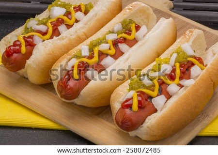 Three Hot Dogs with Mustard, Ketchup, pickle relish and onions