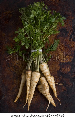 Parsley root with leaves shot from above on a rustic dark background.