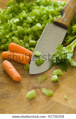 Chopped celery with carrots and knife on cutting board