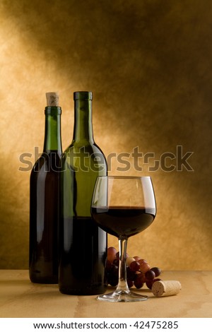 Wine bottles, glass, grapes and cork in simulated wine cellar