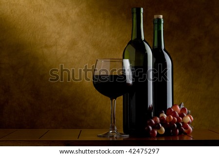 wine glass with wine and two bottles and grapes