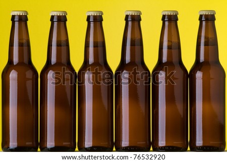 Close up of six bottles of beer on a yellow background