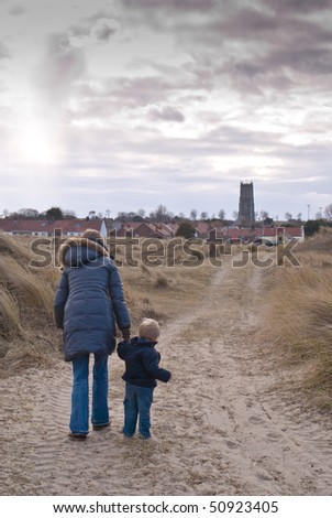 A woman and son walk down an English country path towards a village church