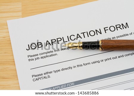 A wooden fountain pen on a wooden desk with a job application form, Applying for a job