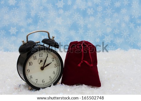 An old-fashion alarm clock with a Santa Bag on snow and a blue snowflake background, It is Christmas Time