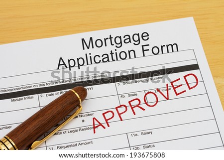 Mortgage Application Form with approved stamp and a pen on a wooden desk