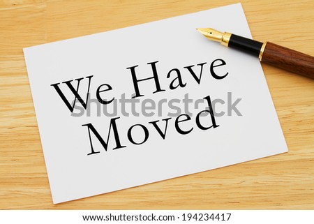 We Have Moved Message, A white card with text of  We Have Moved and a fountain pen on a wooden desk