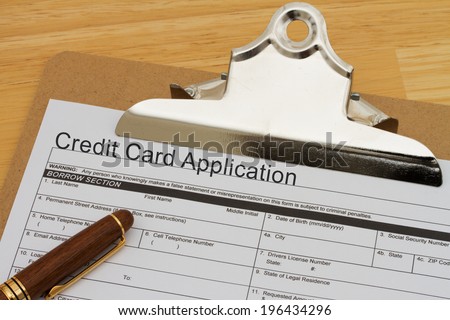 Credit Card Application Form on a clipboard with a pen on a wooden desk