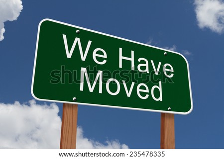 We Have Moved Sign, Green highway sign with words We Have Moved with sky background