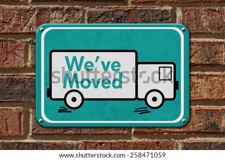 We have Moved Sign,  A teal sign with the word We\'ve Moved with a truck on a brick wall