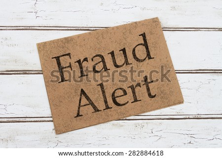 A Fraud Alert Warning Card, A brown card with words Fraud Alert over a distressed wood background