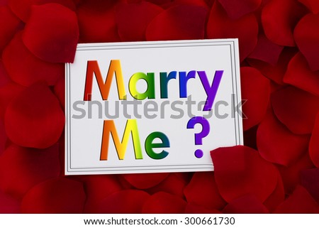 Marry Me Card, A white card with text Marry Me in LGBT pride colors and a red rose pedal backgrounds