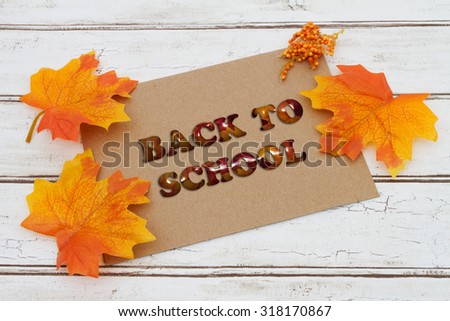 Back to School Sale Card, A brown card with words Back to School Sale over a distressed wood background with Autumn Leaves